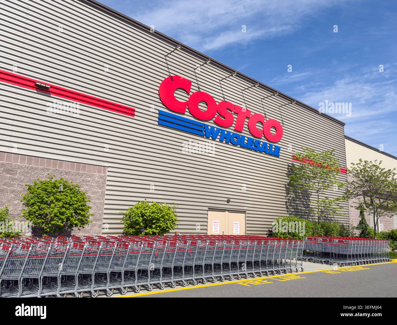 Redmond, WA, USA - 12. Mai 2026; Costco Wholesale Geschäftsschild auf der Seite des Gebäudes mit Einkaufswagen Stockfoto