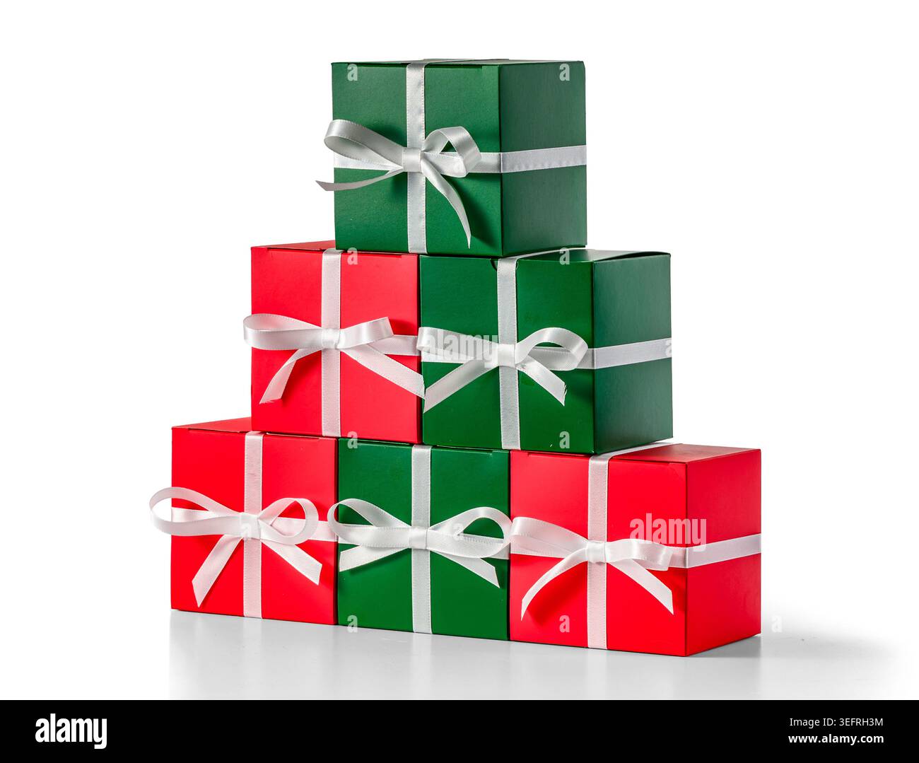 Gestapelte rote und grüne Weihnachtsgeschenke mit weißen Bändern, Studiolit auf isoliertem weiß Stockfoto