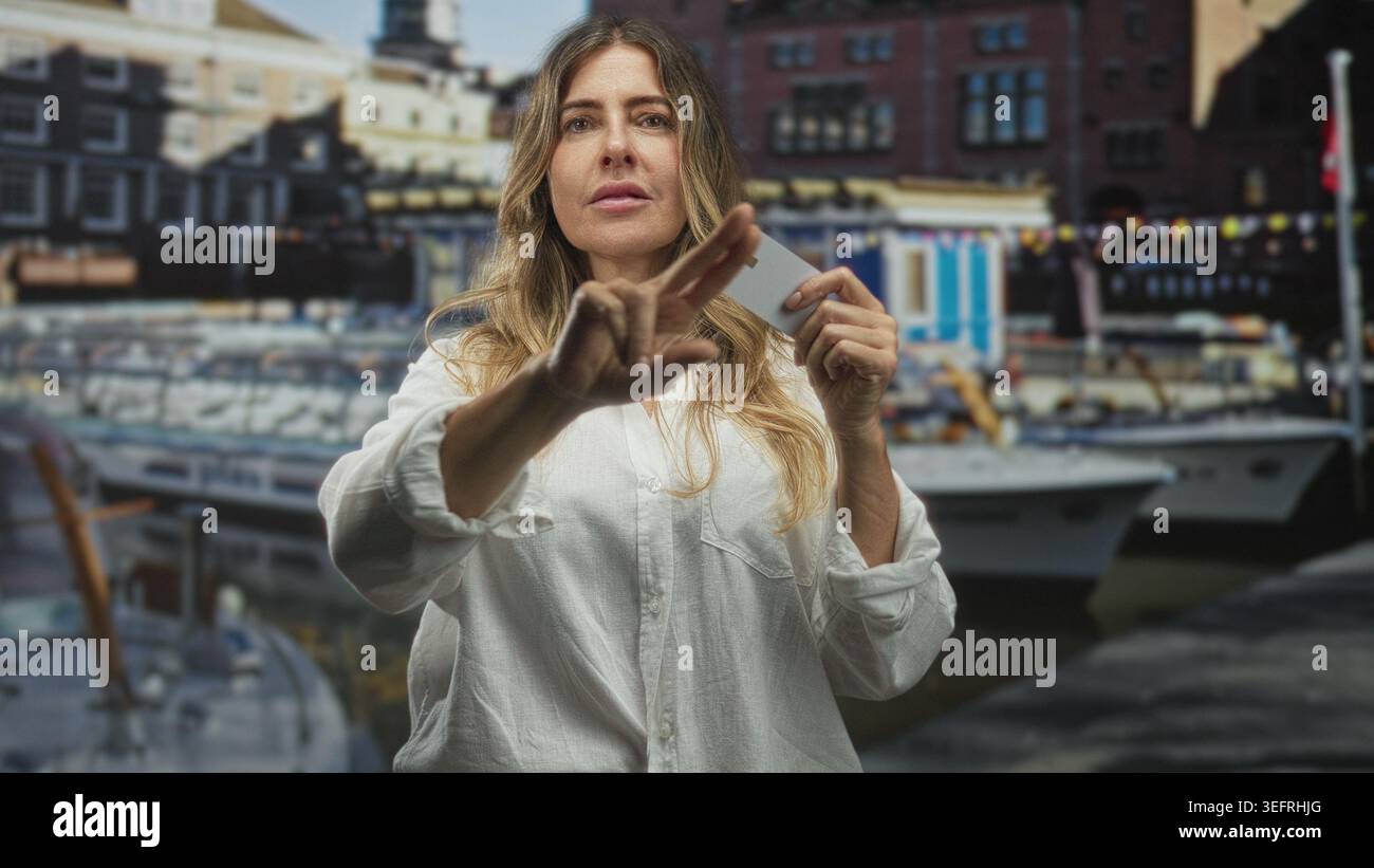 Frau, die eine Kreditkarte hält und mit dem Finger nach vorne zeigt, mit Booten am Hafen; Selbstvertrauen stärken. Stockfoto