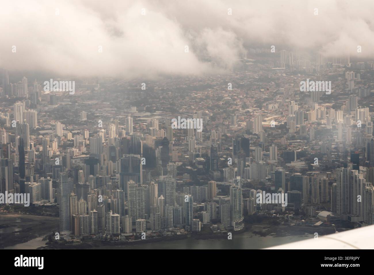 Luftpanorama von Panama City, Panama, mit dichtem Stadtbau, modernen Wolkenkratzern und dramatischen niedrigen Wolken, die einen Teil der Stadt bedecken. Stockfoto