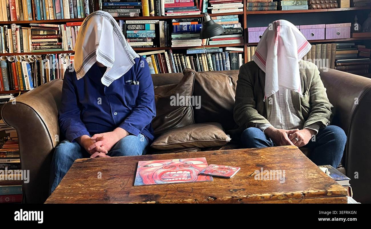Zwei alte Knacker mit Geschirrtüchern auf dem Kopf vergleichen King-Crimson-Musikformate: Vinyl, H2-CD, Tidal-Streaming und eine Red-Book-CD Stockfoto
