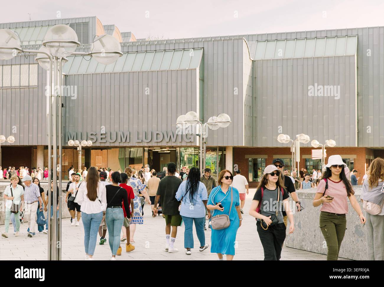 Besucher und Passanten spazieren im Sommer am Museum Ludwig in der westdeutschen Stadt vorbei. Stockfoto