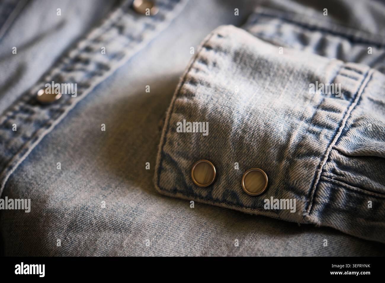 Nahaufnahme: Denim-Hemdmanschette mit Druckknöpfen aus Metall Stockfoto
