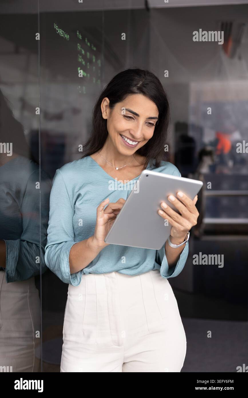 Fröhliche Geschäftsfrau mit digitalem Tablet im modernen Büro Stockfoto