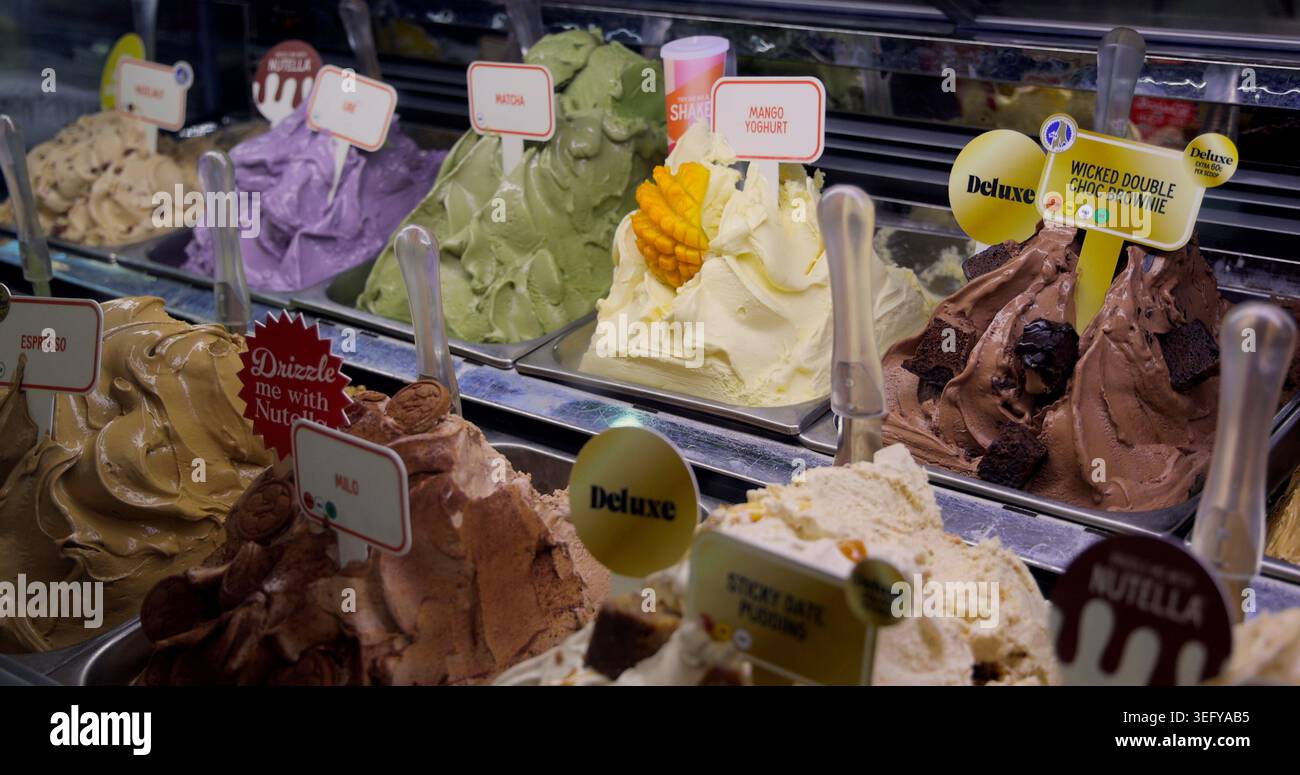 Verschiedene Eisaromen in einer hell beleuchteten Dessertvitrine. Süßer Genuss und köstliches Varieté-Konzept. Verführerische Dessertauswahl. Stockfoto