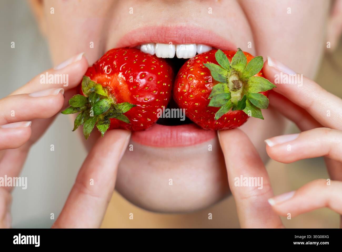 Frau Isst Frische Erdbeeren Aus Nächster Nähe. Nahaufnahme einer Frau, die reife Erdbeeren in der Nähe ihres Mundes hält, frisches Obst zeigt, gesunde Ernährung, und Stockfoto
