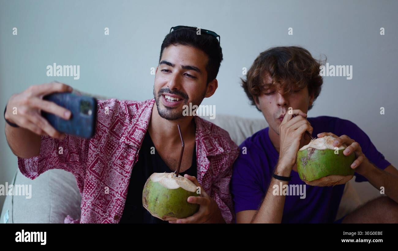 Zwei junge Männer machen Selfie und genießen zusammen frischen Kokosdrink Stockfoto