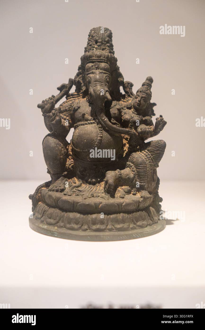 Ganesha mit Shakti. 15. Jahrhundert n. Chr. Bronze. Kerala. Höhe: 12,6 cm, Breite: 9,0 cm, Tiefe: 9,0 cm. Diese vierarmige Figur Ganeshas sitzt auf einem Stockfoto