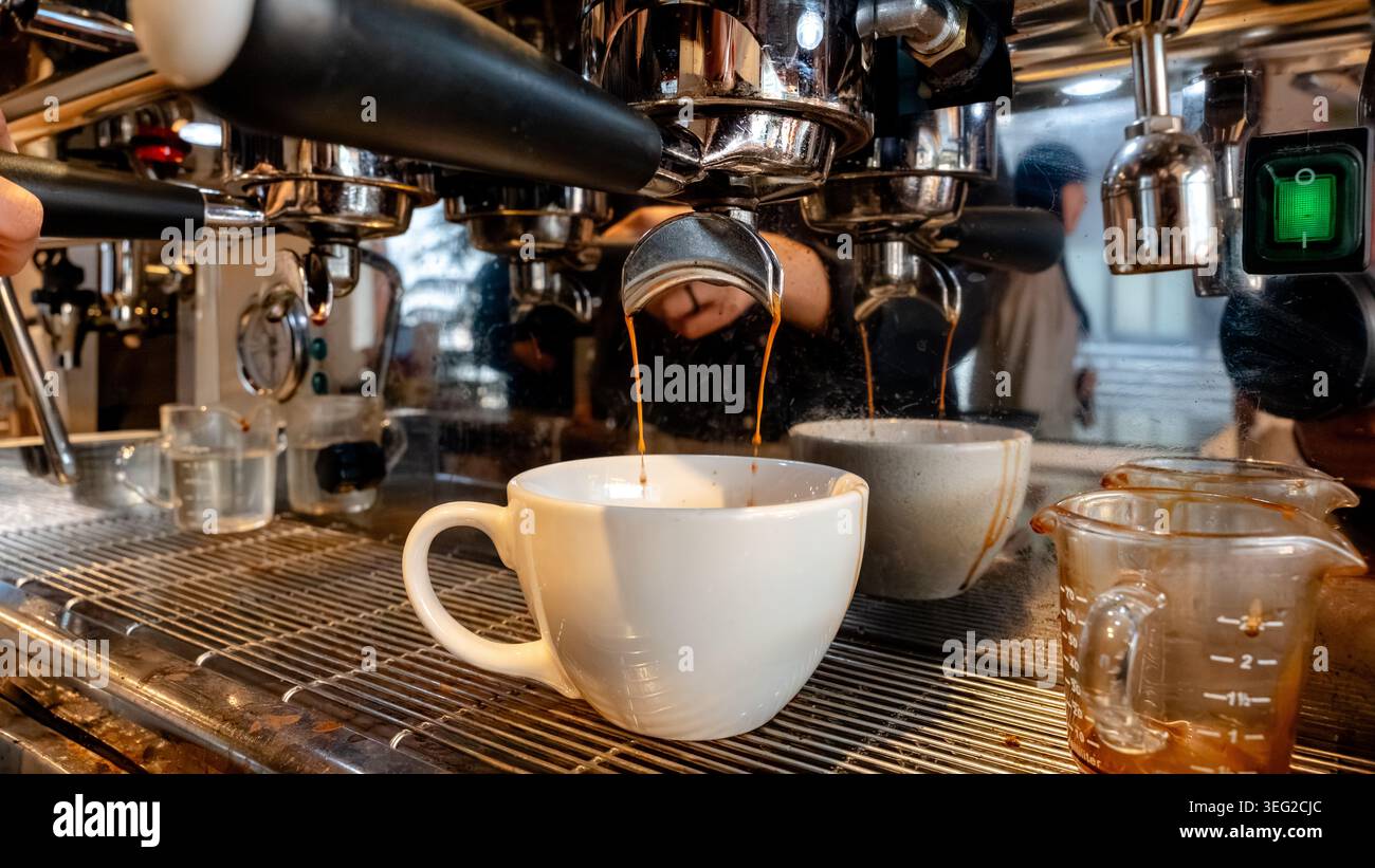 Nahaufnahme eines Espressos, der in einem geschäftigen südkoreanischen Café zubereitet wird und den reichhaltigen, aromatischen Extraktionsprozess und das gemütliche Ambiente unterstreicht Stockfoto