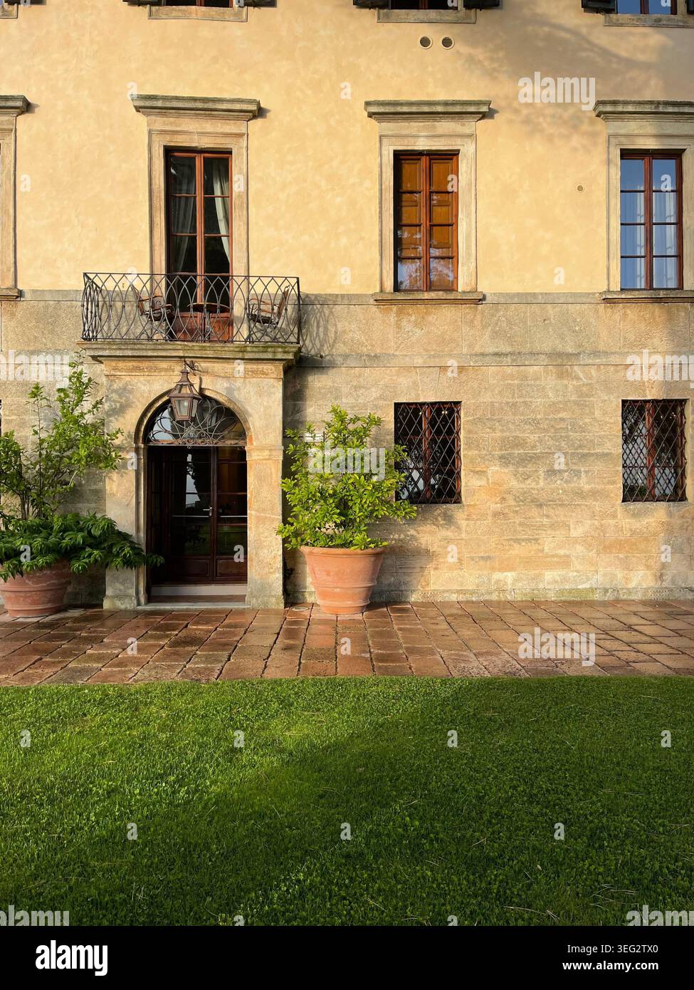Elegante Gärten und die Hauptfassade des Borgo Pignano in der Toskana, die luxuriöse Gastfreundschaft und zeitlosen italienischen Charme bieten. - Smartphone-aufgenommenes Stockfoto