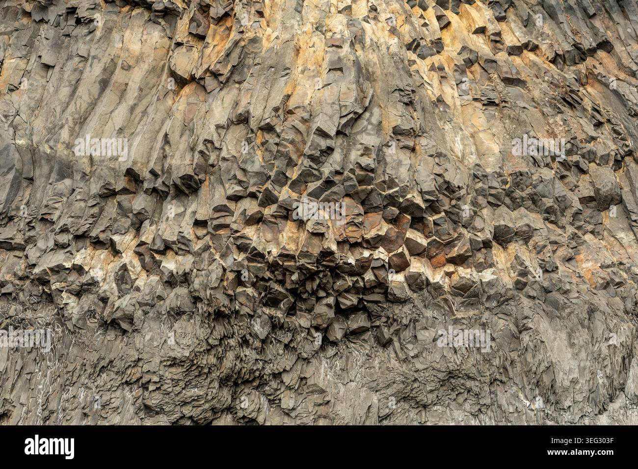 Basaltsäulen, natürliche Säulen aus gehärtetem vulkanischem Gestein, berühmt für ihre geometrischen, oft sechseckigen Formen, die auf Reynisfjara von Moos bedeckt sind Stockfoto