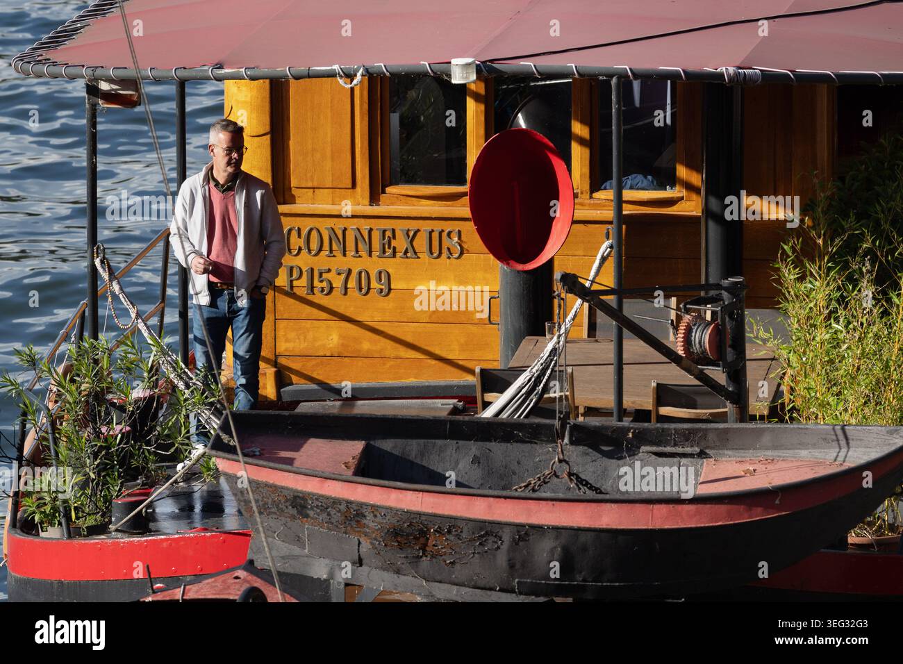 Mann auf dem Deck eines Hausbootes auf der seine in Paris, Frankreich. Stockfoto
