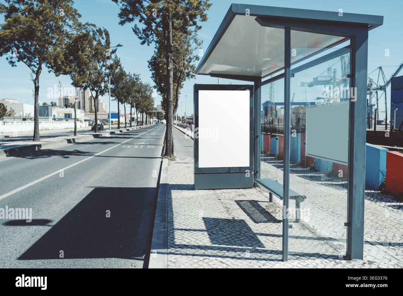 Moderne Bushaltestelle aus Glas mit großem, leerem Posterrahmen auf ruhiger Stadtstraße, realistischem Werbemockup für Kampagne, Branding und Medi Stockfoto