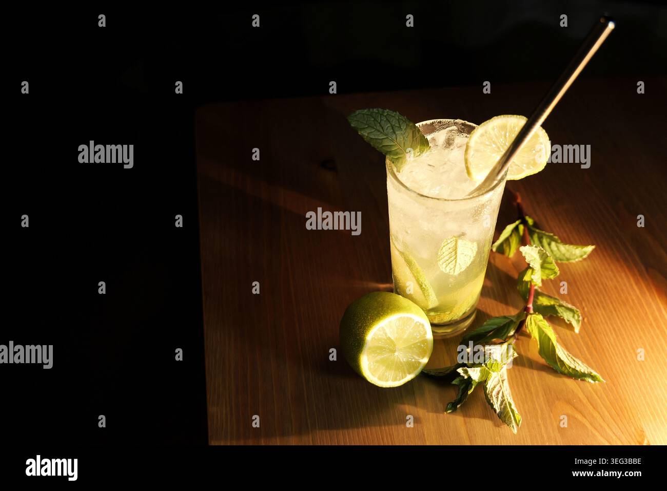 Erfrischender Mojito-Cocktail in einem Glas mit zerstoßenem Eis, frischen Minzblättern, Limettenscheiben und wiederverwendbarem Metallstroh auf einem rustikalen Holz Stockfoto