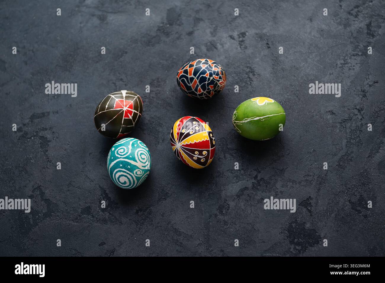 Fünf traditionelle ukrainische Pysanky-Ostereier mit geometrischen und floralen Mustern auf dunkelgrauer Oberfläche. Blick von oben auf handbemalte Eier. Stockfoto