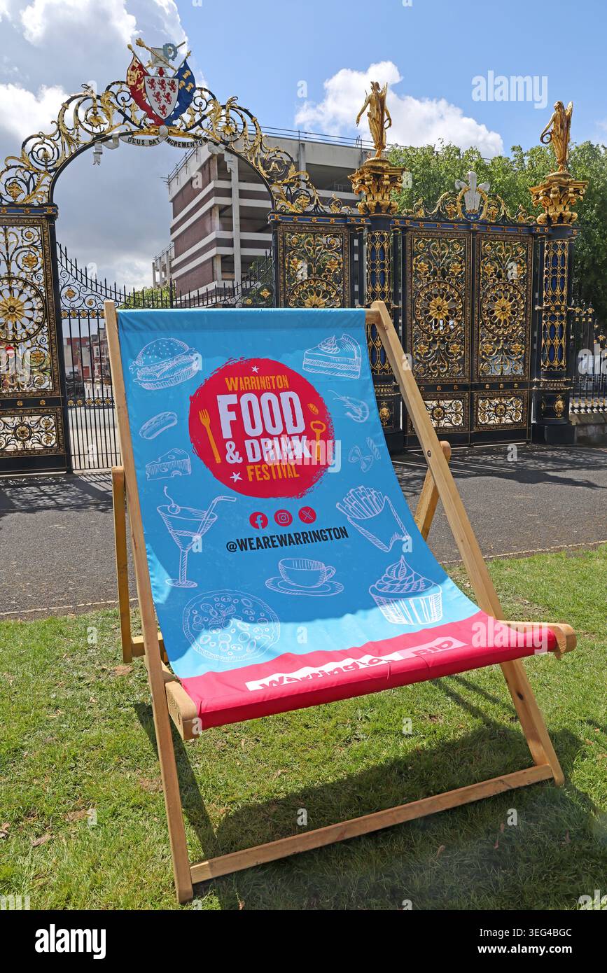 Warrington BID Food & Drink Liegestuhl auf dem Rasen des Bank Park vor den Golden Gates of Town Hall, Warrington, in der Frühlingssonne Stockfoto