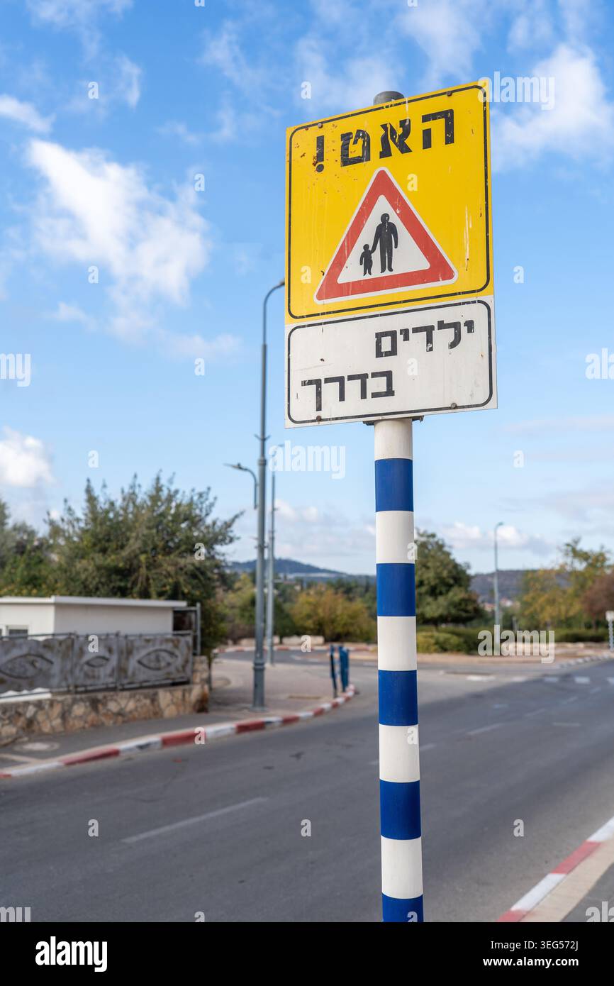 Verkehrssicherheitsschild, das vor Kindern warnt, die in einem ruhigen israelischen Wohnviertel unter hellblauem Himmel unterwegs sind Stockfoto