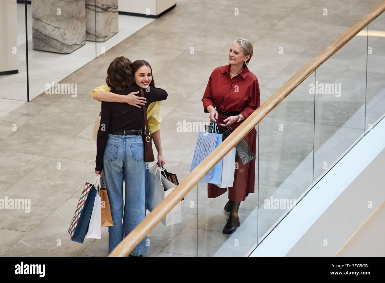 Erwachsene Frauen, die sich während eines Einkaufstages mit einer Seniorin umarmen Stockfoto