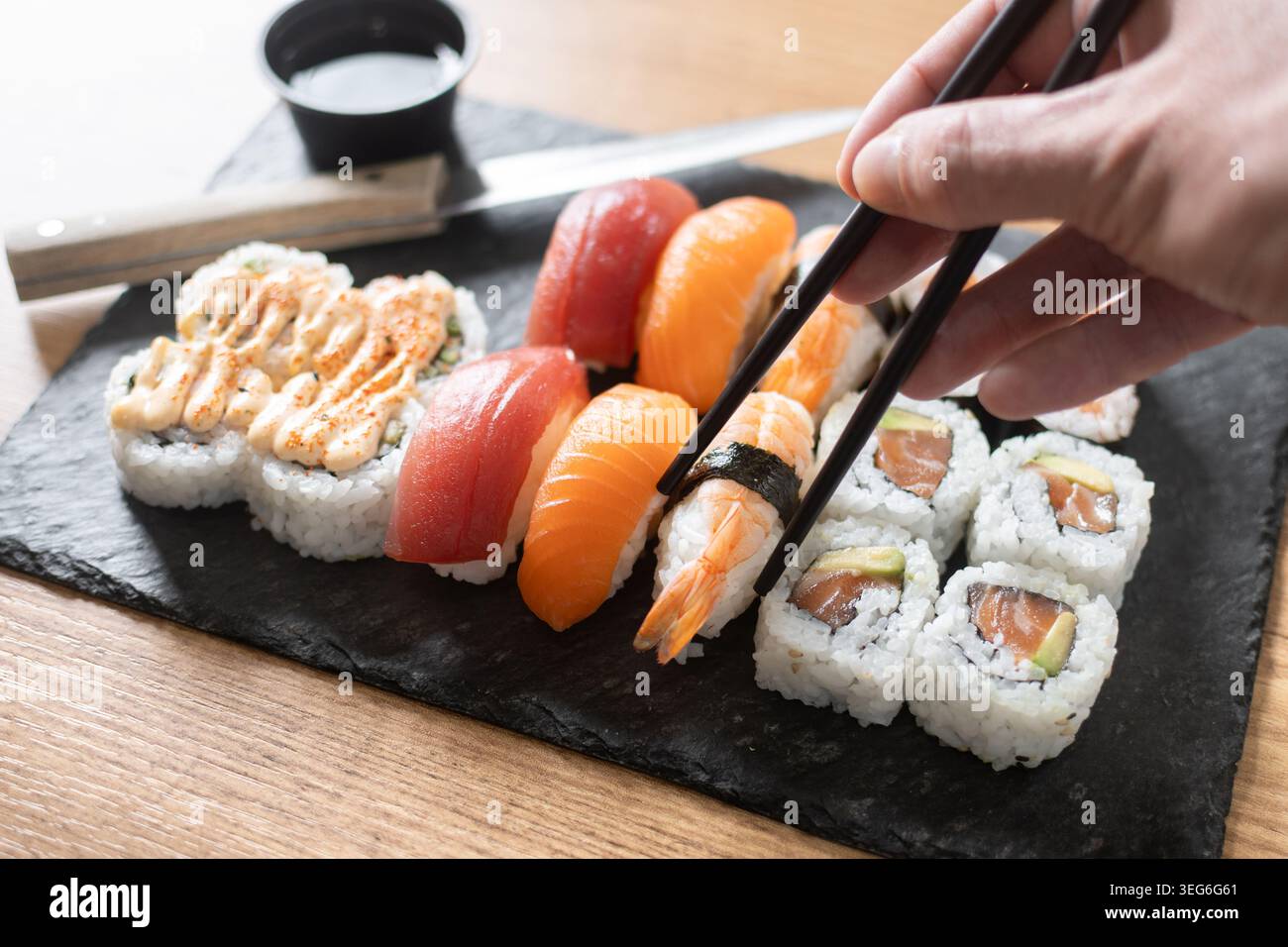 Frau isst Sushi mit Essstäbchen zu Hause Stockfoto