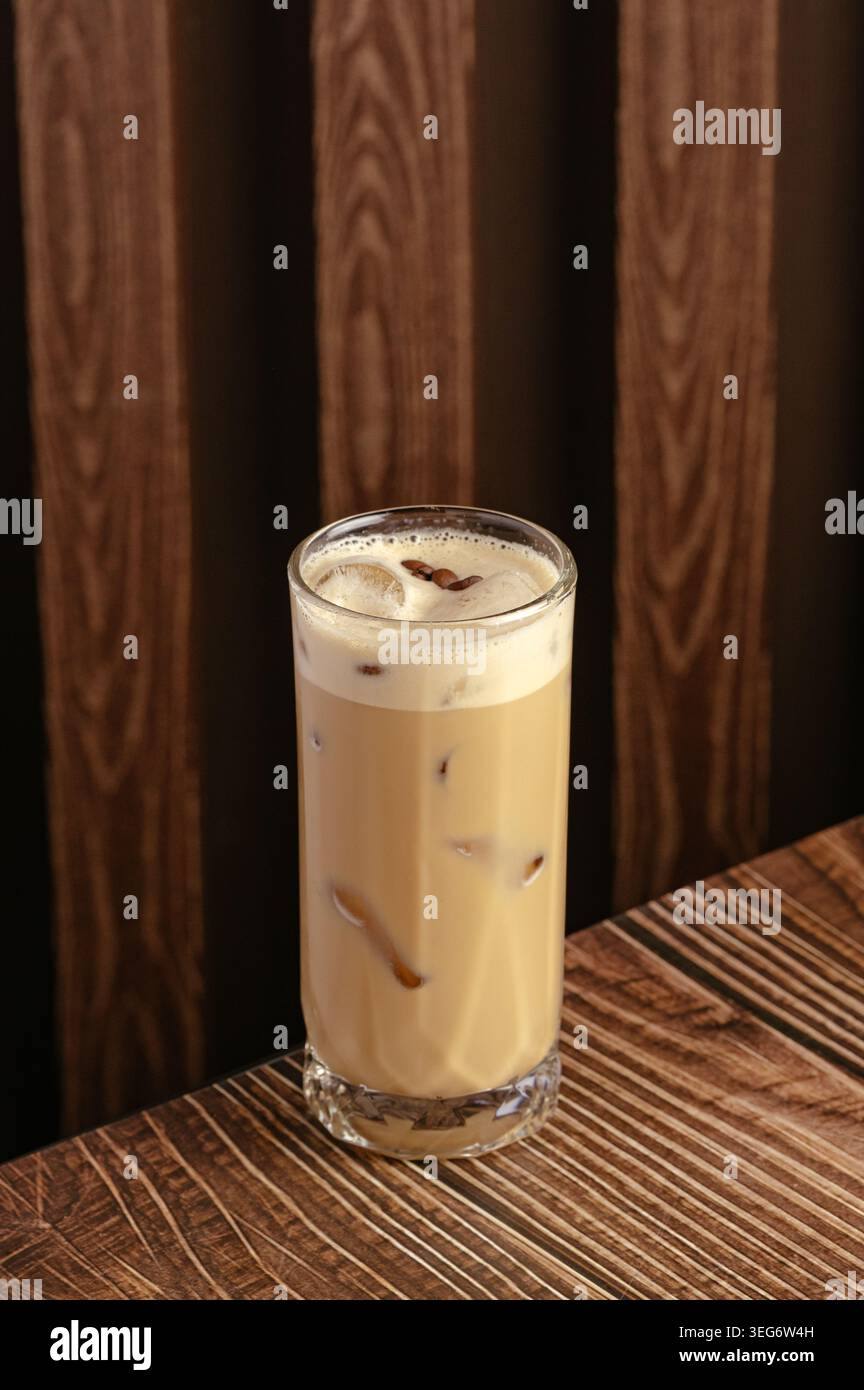 Ein großes Glas Eiskaffee auf einem dunklen Holztisch Stockfoto