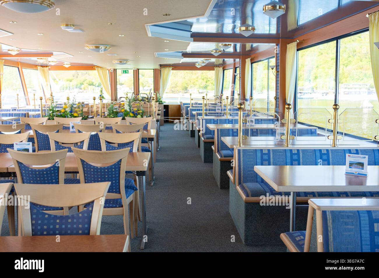 Helles Restaurant mit Tischen und Stühlen im modernen Passagierschiff. Gemütlicher Essbereich mit Panoramafenstern und Tageslicht. Stockfoto