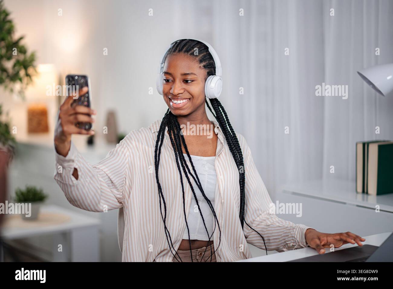 Junge Erwachsene Frau, die Selfie mit Smartphone und Kopfhörern macht Stockfoto