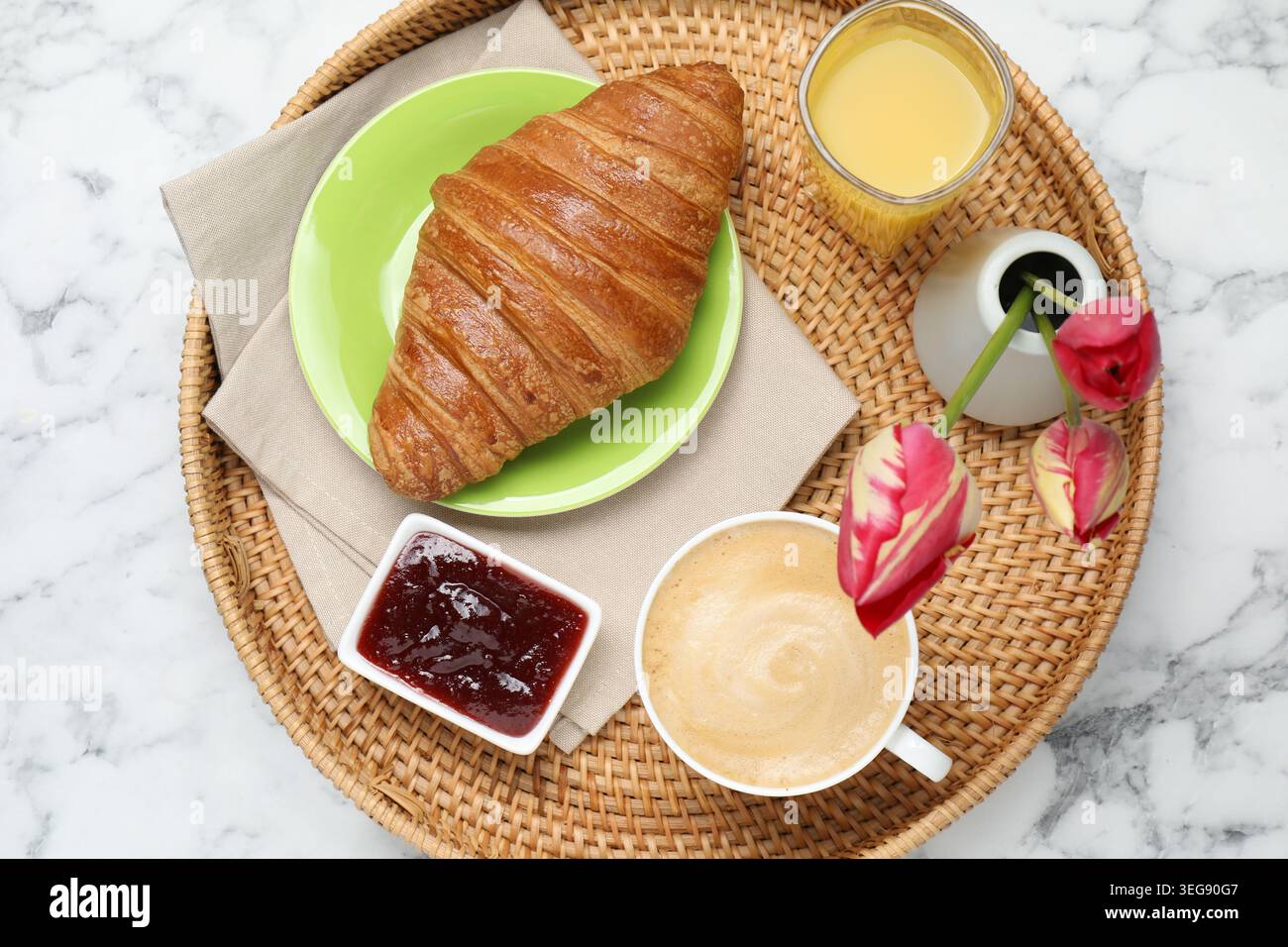 Tablett mit leckerem Frühstück und Tulpenblumen auf weißem Marmortisch, Blick von oben Stockfoto