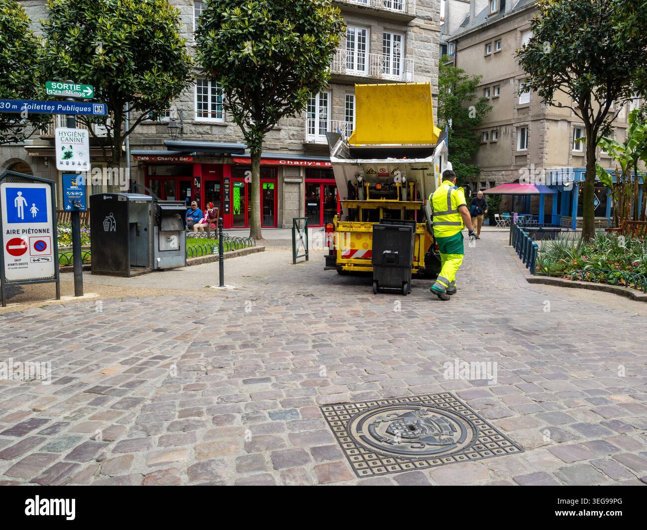 Kommunale Sanitärangestellte, die Mülltonnen auf einer Stadtstraße in Frankreich leeren. Alltägliche urbane Szene, die Sauberkeit, Instandhaltung und Abfallwirtschaft zeigt Stockfoto