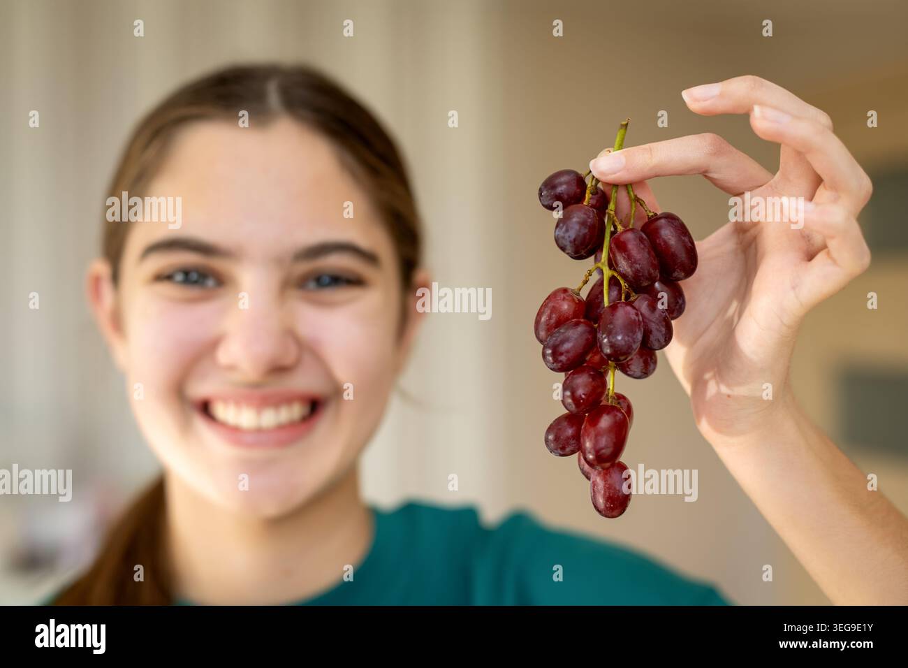 Lächelnde Person, Die Frische Rote Trauben Hält. Lächelnde Person, die einen Haufen frischer roter Trauben hält, wobei gesunde Ernährung, Obstsnacks und natürlich hervorgehoben wird Stockfoto