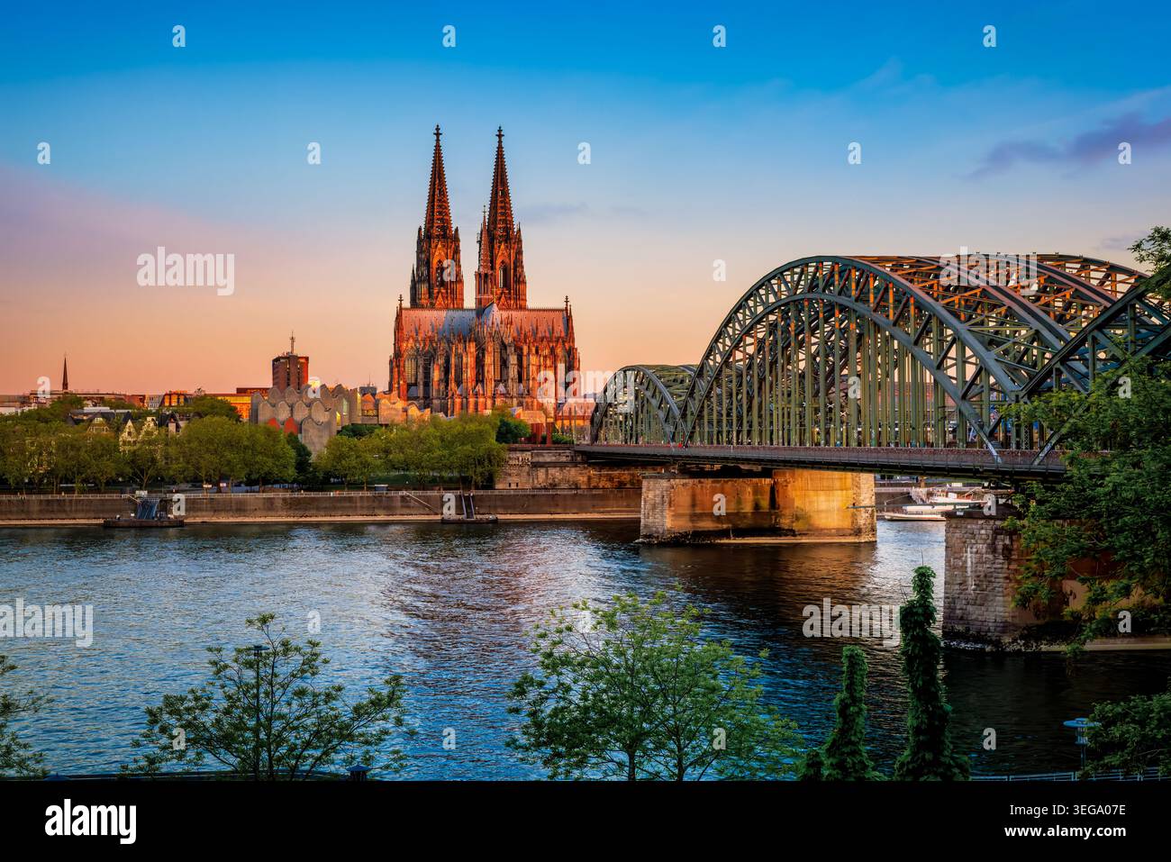 Wunderschöner Blick auf den Sommersonnenaufgang auf das Stadtbild von Köln, Deutschland, mit Dom und Hohenzollernbrücke in goldener Morgensonne Stockfoto