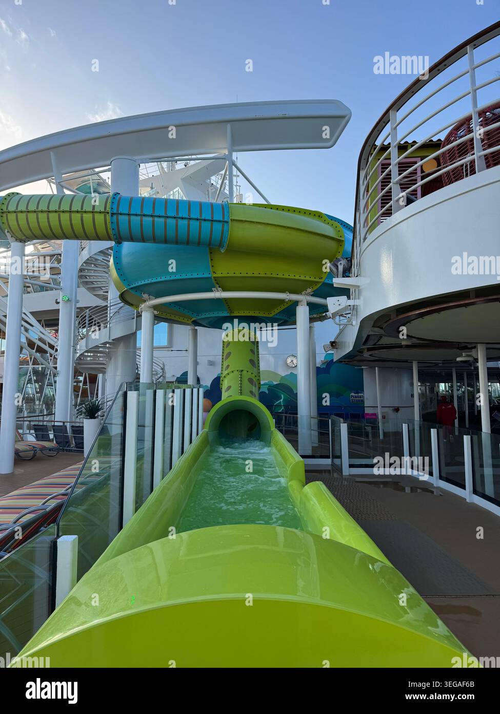 Wasserrutschen auf dem Kreuzfahrtschiff. Innenansicht aus nächster Nähe mit Blick auf einen hellgrünen Kunststoff-Wasserrutschkanal auf einem Schiffsdeck. Stockfoto
