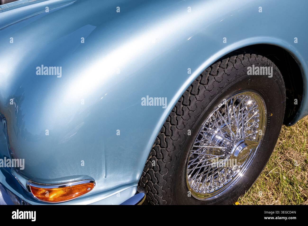 Blassblauer Oldtimer-Frontflügel mit Chromdrahtrad, orangefarbener Anzeige und antiretrospektivem Reifen bei Sonneneinstrahlung im Freien Stockfoto