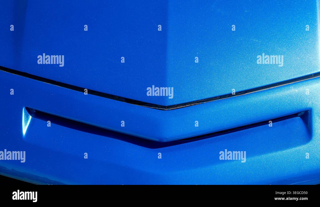 Die Fahrzeugkarosserie in leuchtendem Blau mit einer scharfen V-förmigen Blende und einer Bügelfalte sorgt für auffällige abstrakte geometrische Details Stockfoto