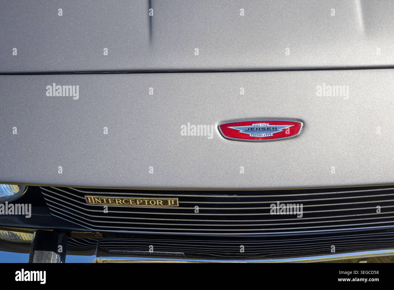 Motorhaubenabzeichen und Kühlergrill des Jensen Interceptor II Oldtimer mit rotem Emaillogo auf silbergrauer Karosserie Stockfoto