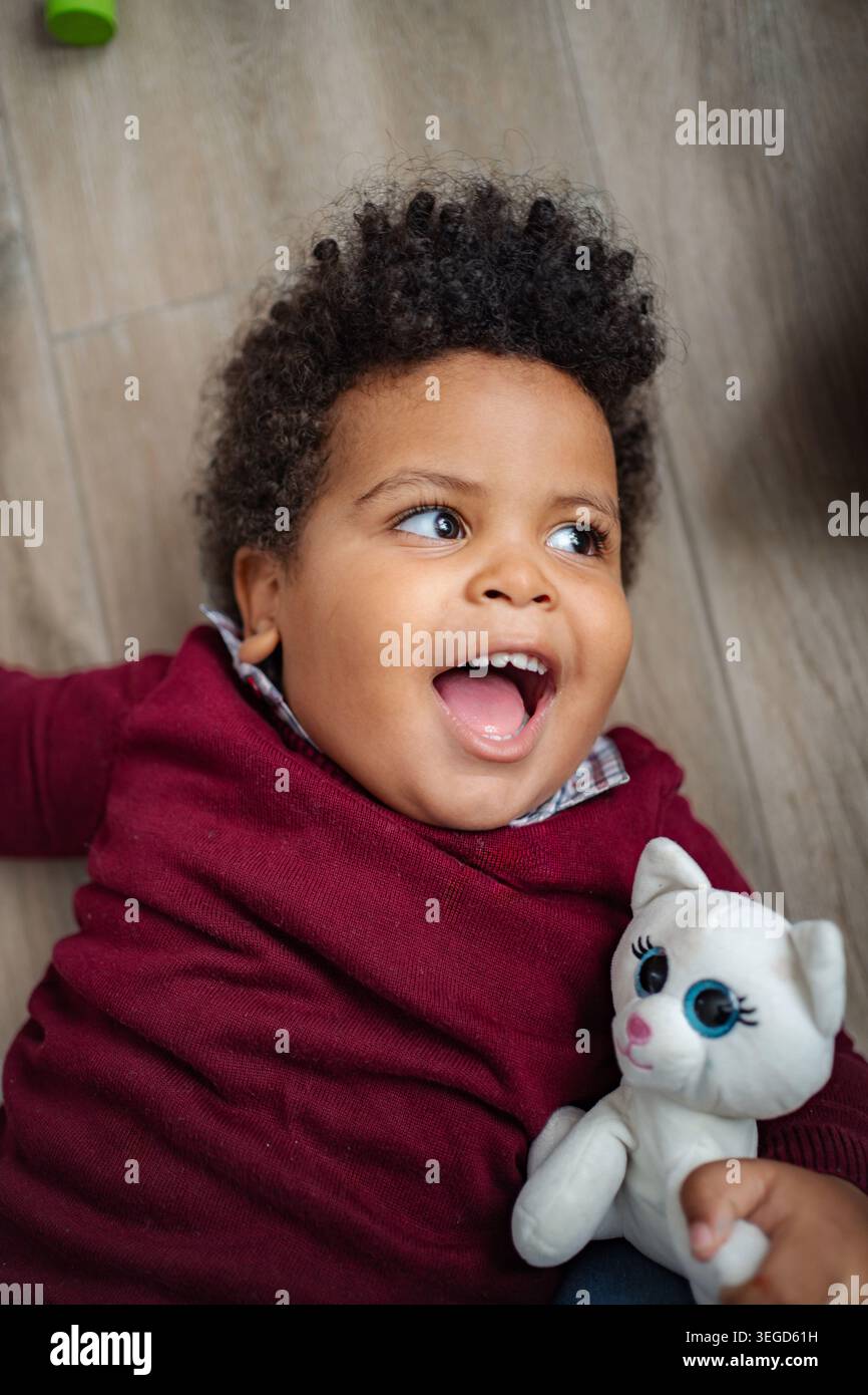 Fröhliches Baby lacht und genießt Spielzeit mit Plüschtier Stockfoto