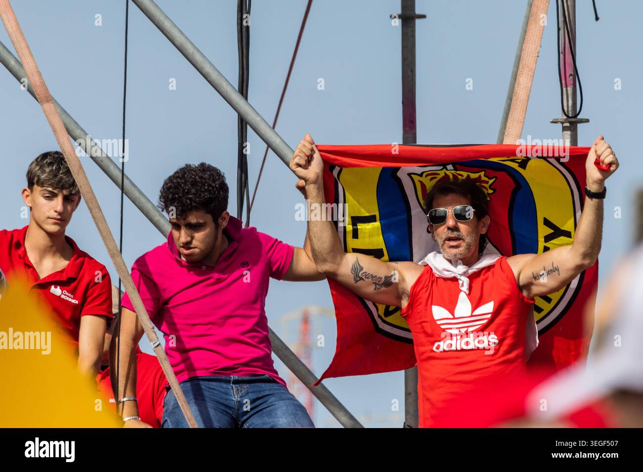 Mqabba, Malta - 17. Mai 2026, begeisterte Fußballfans jubeln mit Teamflagge und rotem Adidas-Shirt beim Outdoor-Spiel Stockfoto