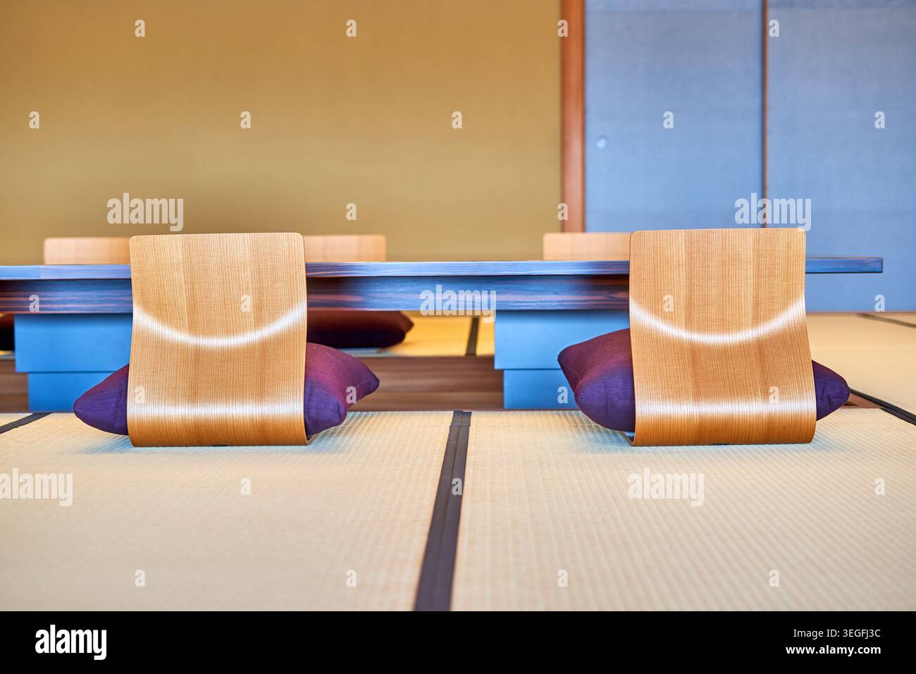 Moderner japanischer Innenraum mit traditionellem Tatami-Mattenboden und zeitgenössischen geschwungenen Holzbodensesseln, die für das Seiza-Sitzen konzipiert sind Stockfoto
