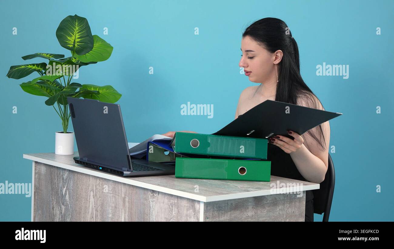 Selbstbewusste Geschäftsfrau, die Mappe hält und am Bürotisch denkt Stockfoto