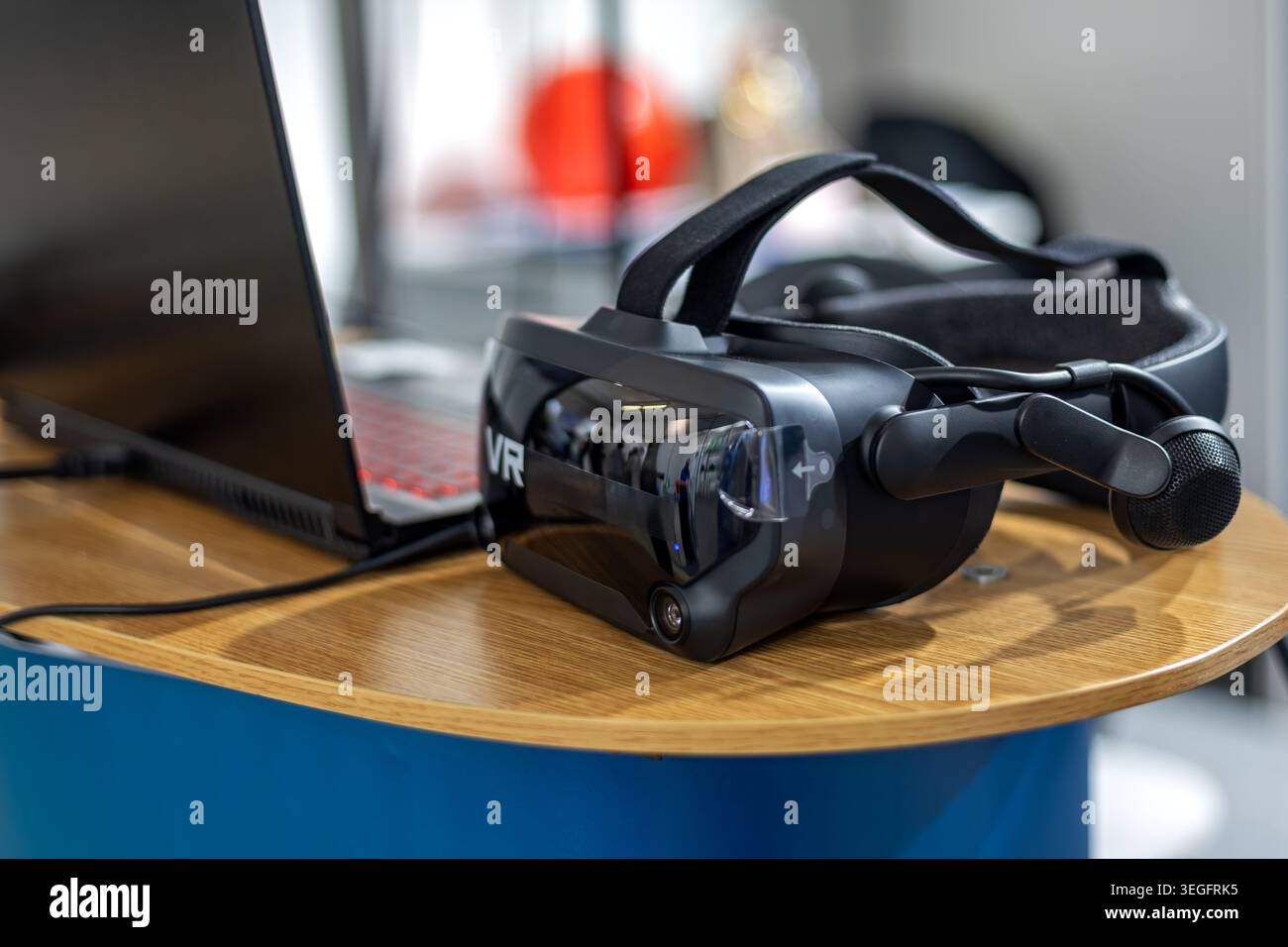 Virtual-Reality-Headset neben dem Notebook. Nahaufnahme eines VR-Headsets mit Mikrofon neben einem Laptop mit immersiver Technologie, Simulation und Stockfoto