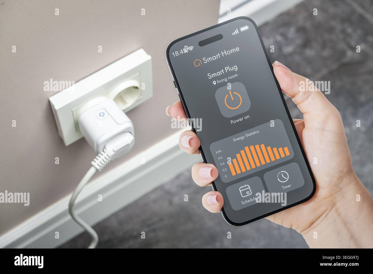 Handheld-Smartphone mit Smart-Home-Anwendungsschnittstelle, die Statistiken zur Energieüberwachung und intelligente Plug-Steuerung mit einer Smart-Buchse o anzeigt Stockfoto