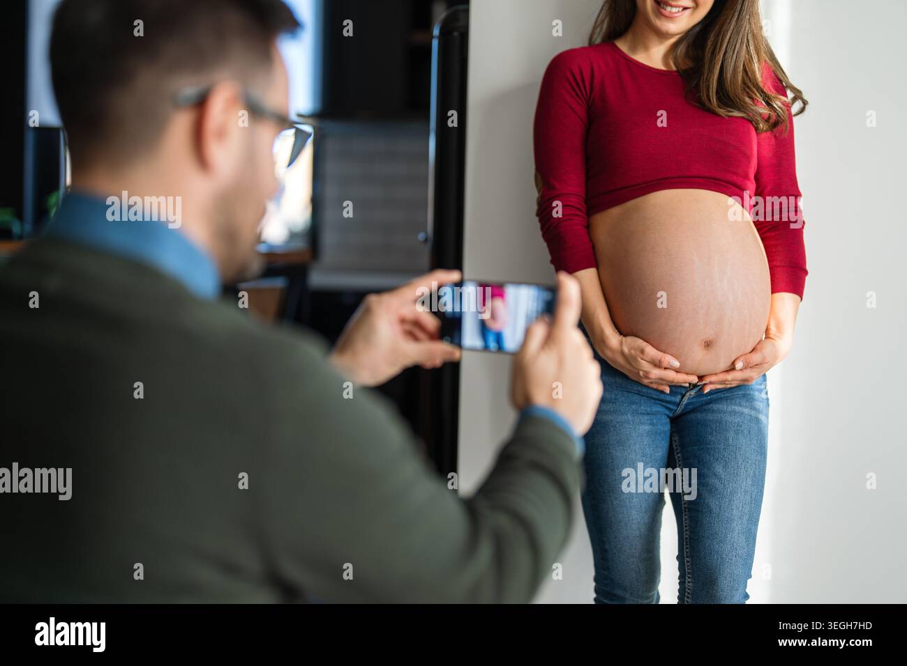 Multiethnische glückliche schwangere Paare benutzen Handy für Vloggen, Fotos machen, online kommunizieren Stockfoto