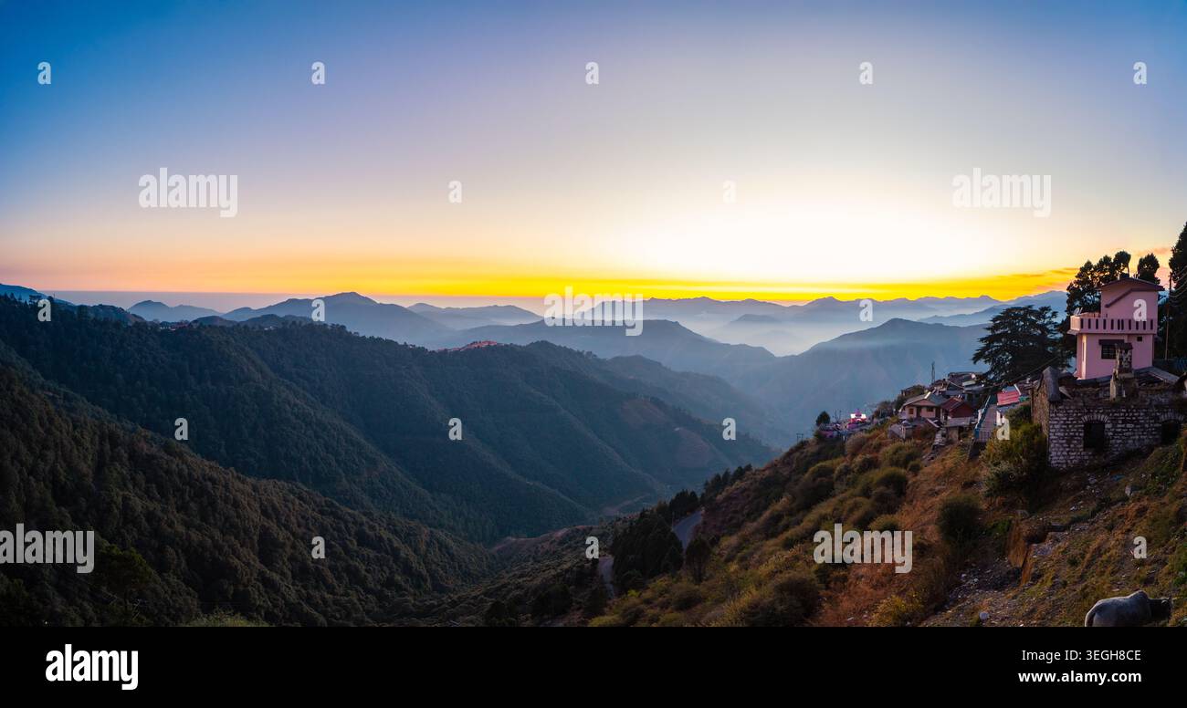 Ein großer Panoramablick auf die Himalaya-Bergkette während eines goldenen Sonnenaufgangs mit einem kleinen Dorf auf dem Hügel in Chakrata, Uttarakhand, I Stockfoto