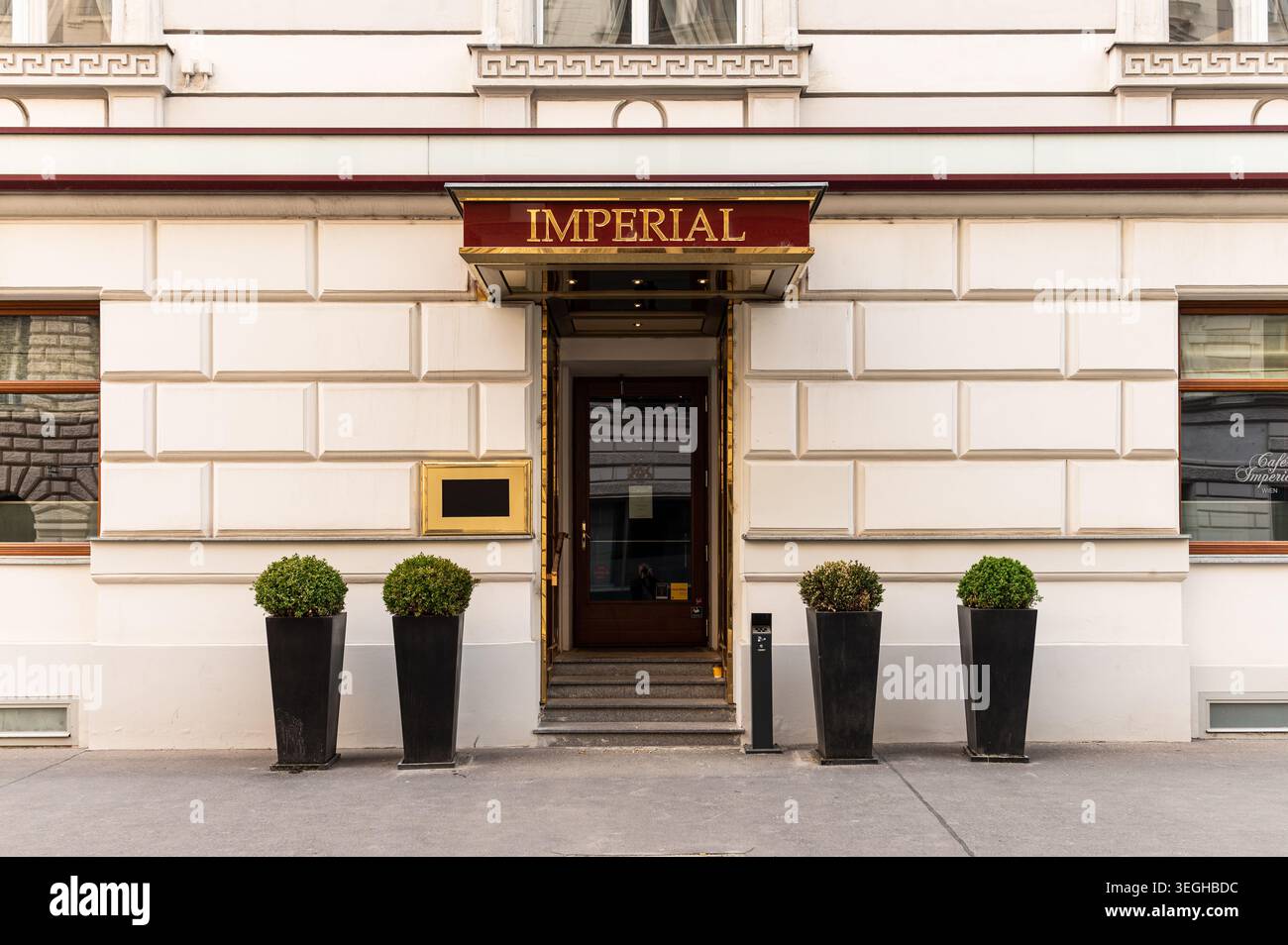Wien, Österreich - 23. Mai 2020: Goldenes Imperial-Schild hängt über der hölzernen Glastür seitlich am Eingang des luxuriösen Vienna Hotel Imperial, flankiert von schwarzem Band Stockfoto