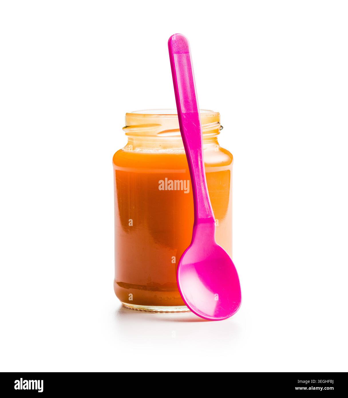 Ein Glas mit glatter orangener Babynahrung kombiniert mit einem knallrosa Löffel, das an hausgemachtes Püree, gesunde Ernährung für Kleinkinder, einfaches Löffeln und Colo erinnert Stockfoto