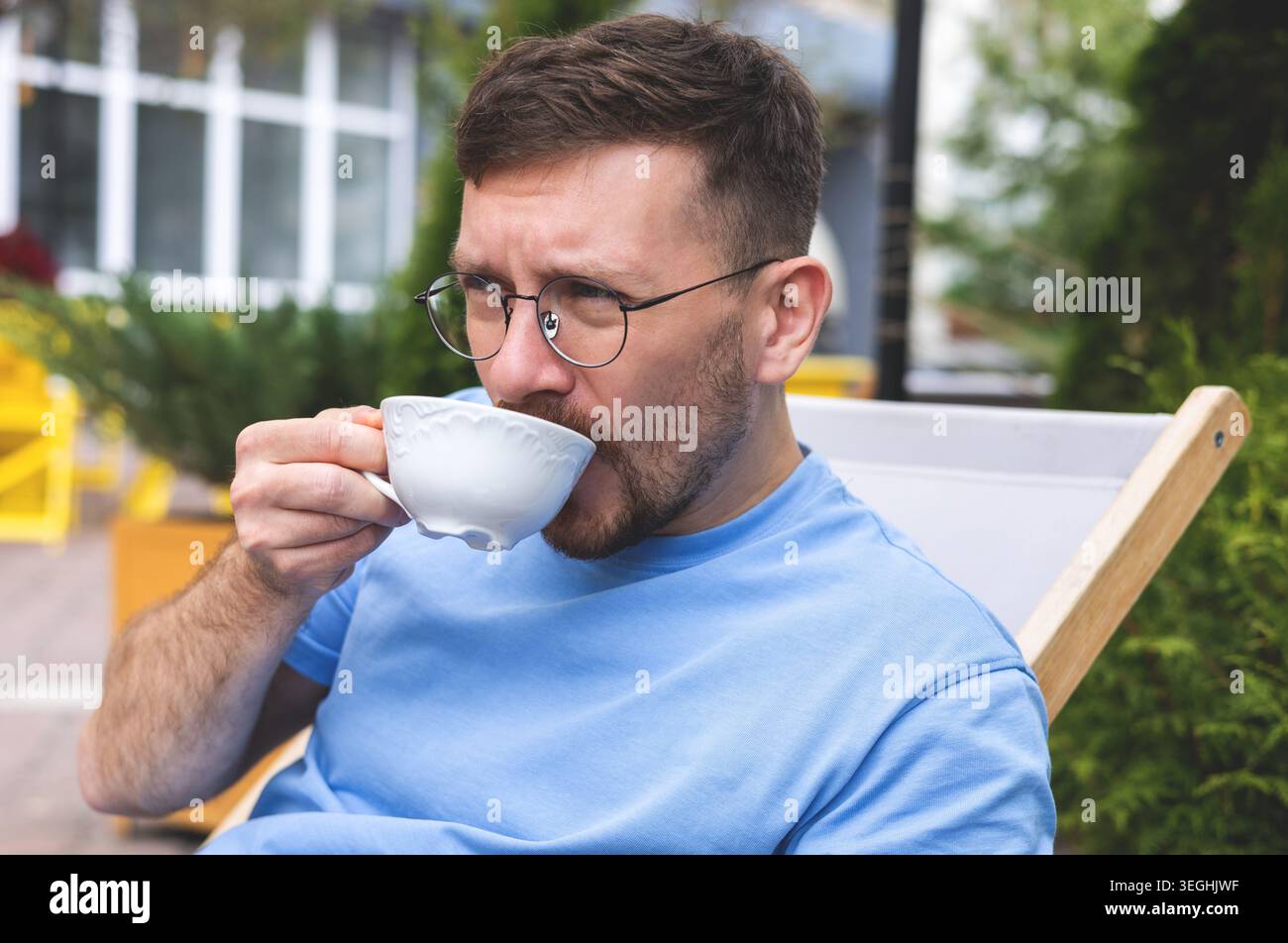 Ein junger Mann trinkt Morgenkaffee auf einer Terrasse Stockfoto