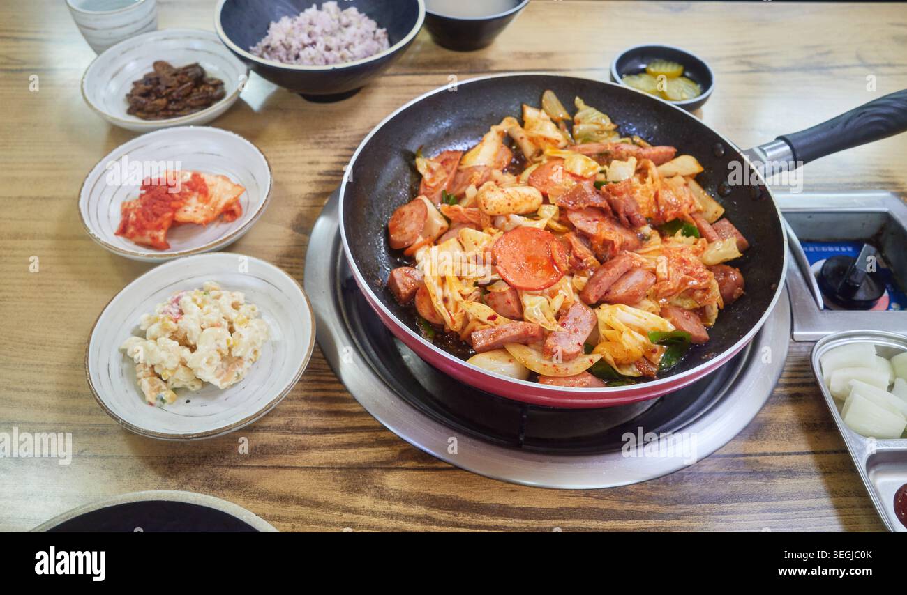 Das würzige Uijeongbu Budae-bokkeum bietet verschiedene Würstchen und gebratenen Schinken mit Kohl. Kombiniert mit Ramyeon-Nudeln und traditionellen Beilagen für ein Herz Stockfoto