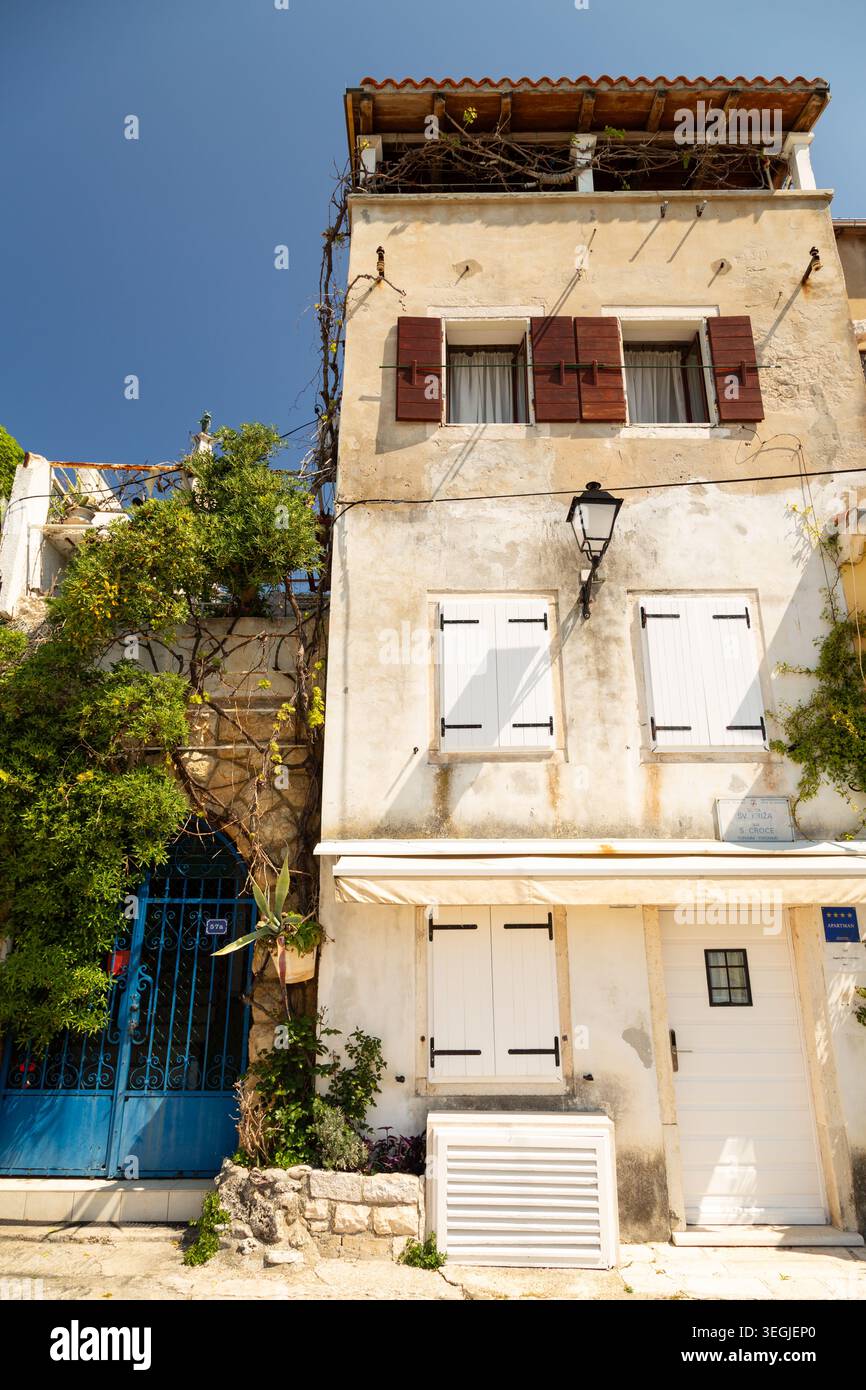 Dreistöckiges Wohngebäude mit Fensterläden und einem blauen schmiedeeisernen Tor in der Altstadt von Rovinj, Kroatien. Stockfoto