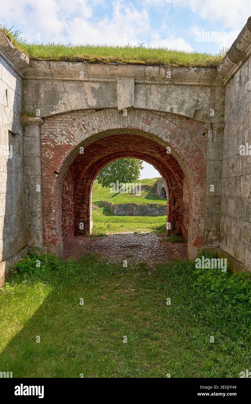 Der Steinbogen umrahmt die grüne Landschaft in den Ruinen der antiken Festung. Stockfoto