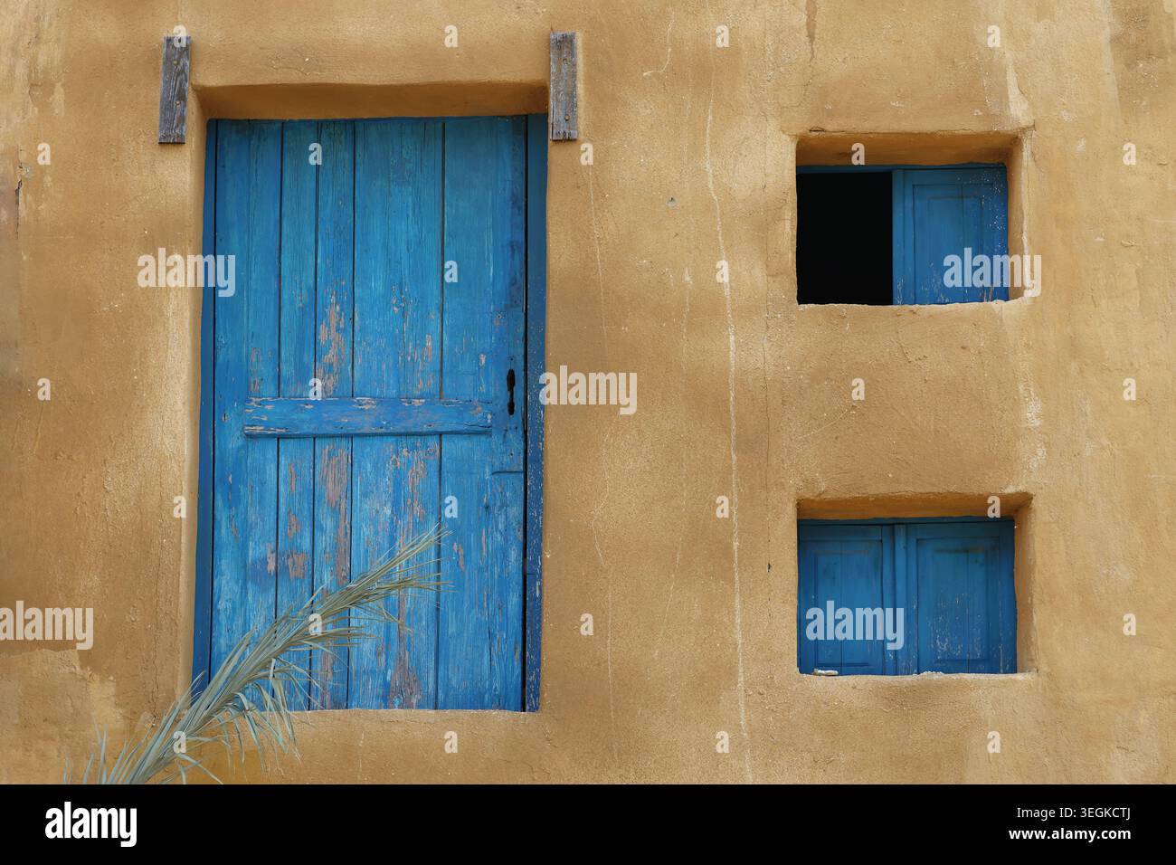 Eine geschlossene Holztür mit abblätternder Farbe und zwei kleinen Fenstern. Stockfoto