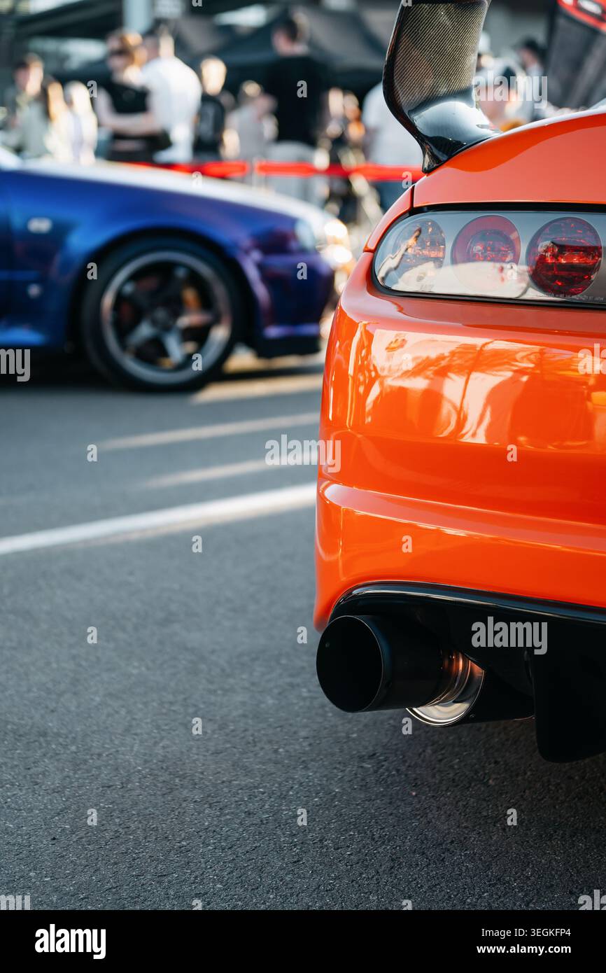 JDM Car Meet – Treffen japanischer Autobesitzer – hinterer linker Teil des orangen Toyota Supra A80 und vorderer Teil des lila Nissan Skyline R34 GT-R. Stockfoto